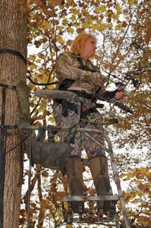 Joella Bates, a world champion archer prepares to take a shot at a deer while hunting from a traditional tree stand.