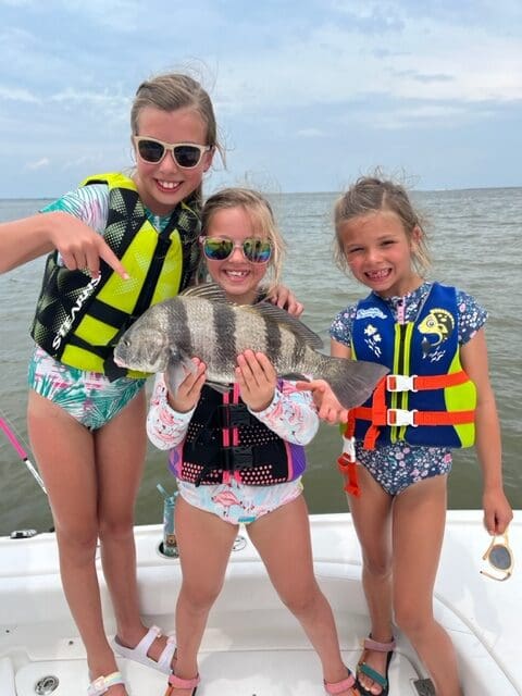 Ava Cox, Stella Cox, and Cameron Nichols show off a nice black drum caught while they were fishing on their Papa’s boat in Trinity Bay.